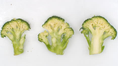 In-slow-motion-splashes-of-water-pour-water-on-a-beautiful-juicy-vegetables-a-lot-of-broccoli-on-a-white-background.-Vegetarian-and-Fructorians.